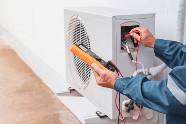 HVAC technician performing electrical diagnostics on an outdoor air conditioning unit in Las Cruces, NM, to ensure safe and efficient operation.